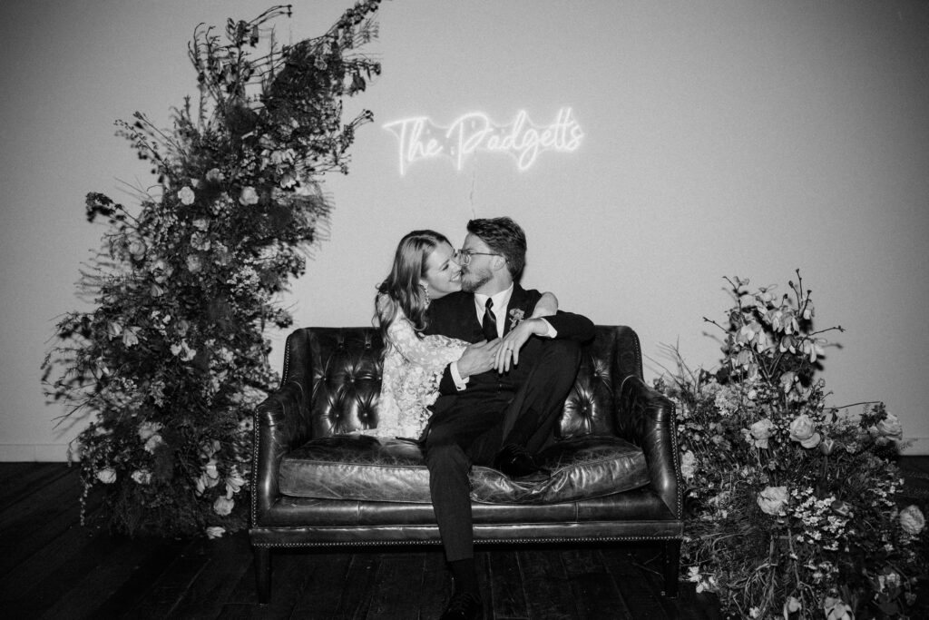 bride and groom at their wedding sharing a kiss under a neon sign