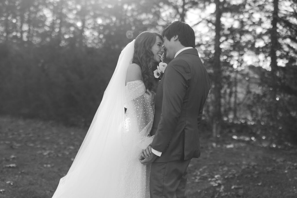 Bride and groom touching faces and smiling after seeing each other for the first time on their wedding day.