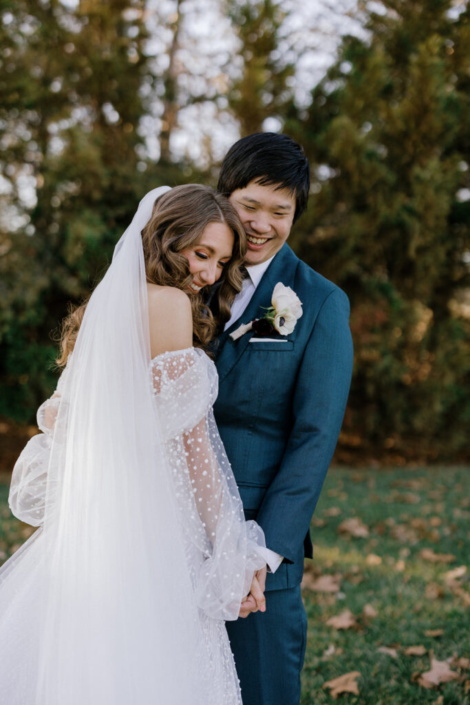 Bride and groom laughing while leaning into each other.