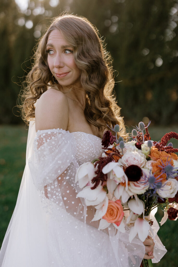 The bride looking over her shoulder while holding her bouquet.