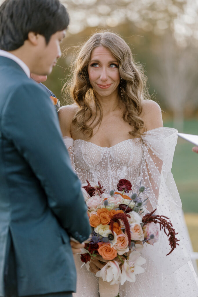 The bride arriving at the altar and smiling at her groom. 