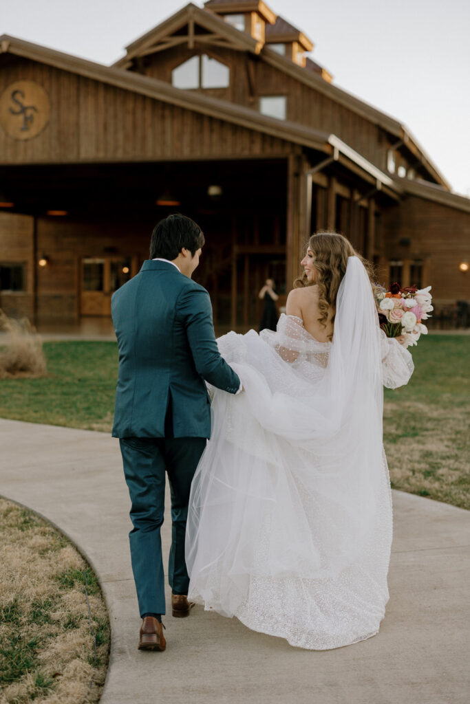 The bride and groom walking down the aisle with big smiles. The groom is holding her dress train as she walks. 