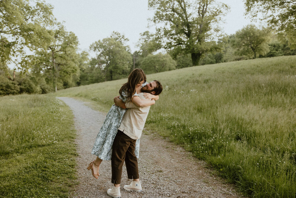 A couple hugs standing on a gravel path while smiling