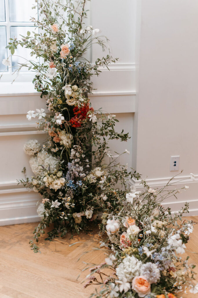 A gallery window with two framing floral installations forming an arch