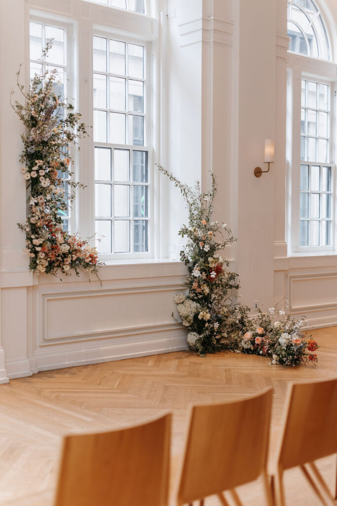 A wedding ceremony with two framing floral installations forming an arch