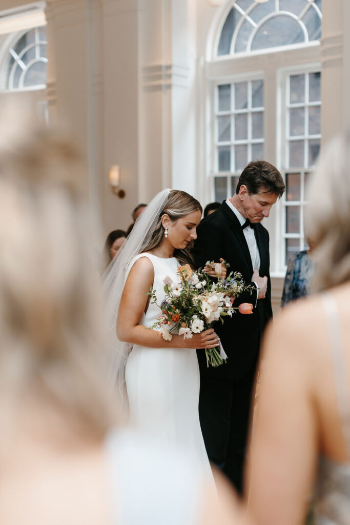 A bride and her father bow their heads to pray