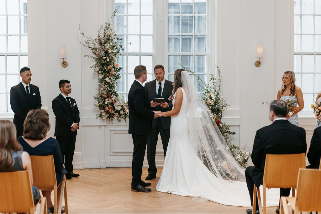 A wedding ceremony with two framing floral installations forming an arch