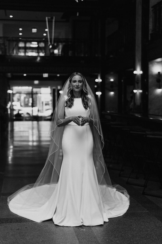 A bride in a white dress with the train extended, her veil placed around her, and she is waiting patiently