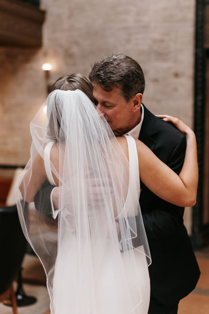 The bride and her father hug tightly