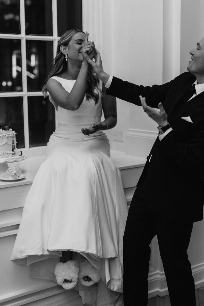 A bride and groom laugh at each other during the wedding cake cutting