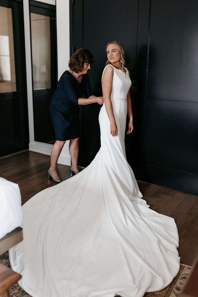 The mother of the bride buttoning her daughter's dress