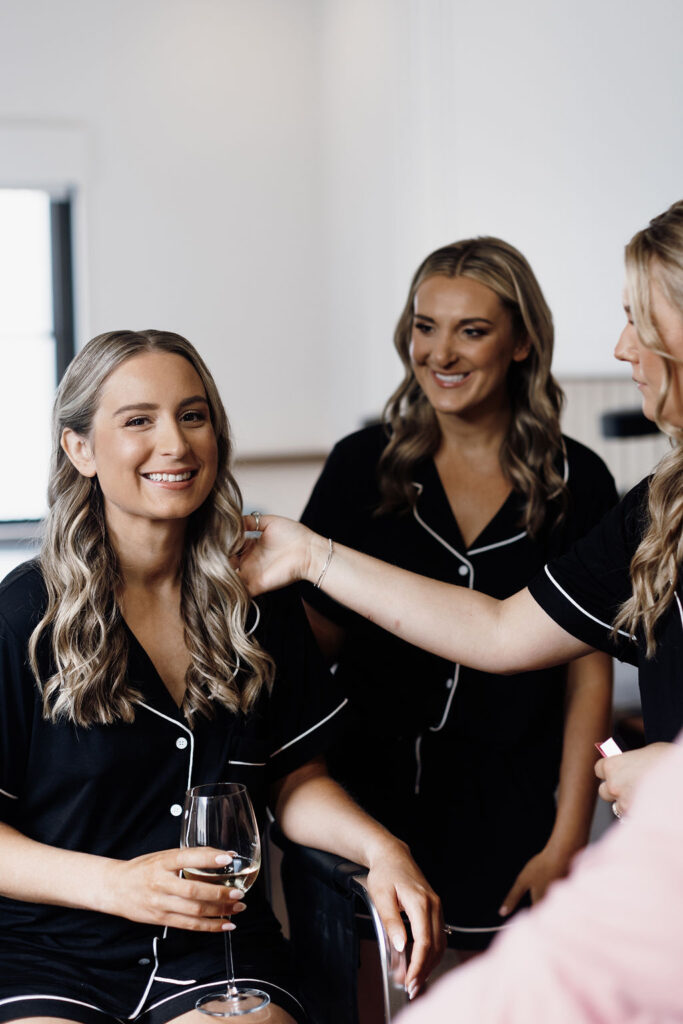 Three blonde women smiling and admiring the bride's hairstyle